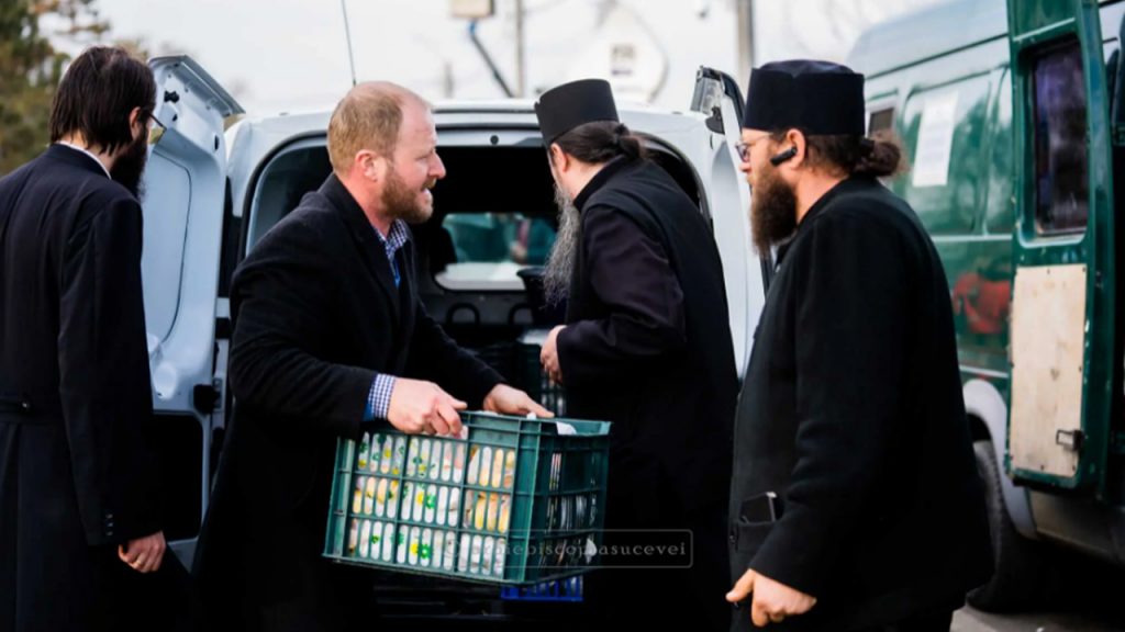 Voluntari și preoți ai Arhiepiscopiei Sucevei oferă ajutor umanitar refugiaților ucraineni, distribuind alimente și produse de igienă în cadrul unui centru de sprijin.