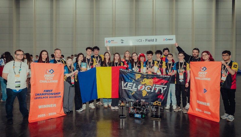 Echipa României câștigătoare la FIRST Tech Challenge Championship, cu trofee, steag și robot de competiție